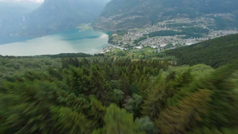 Vuelo-Aéreo-Cuesta-Abajo-Por-Las-Montañas-Verdes-Hacia-La-Ciudad-Turística-De-Odda-Y-Fiordo-En-Noruega---Tiro-Dinámico-De-Drones-Fpv