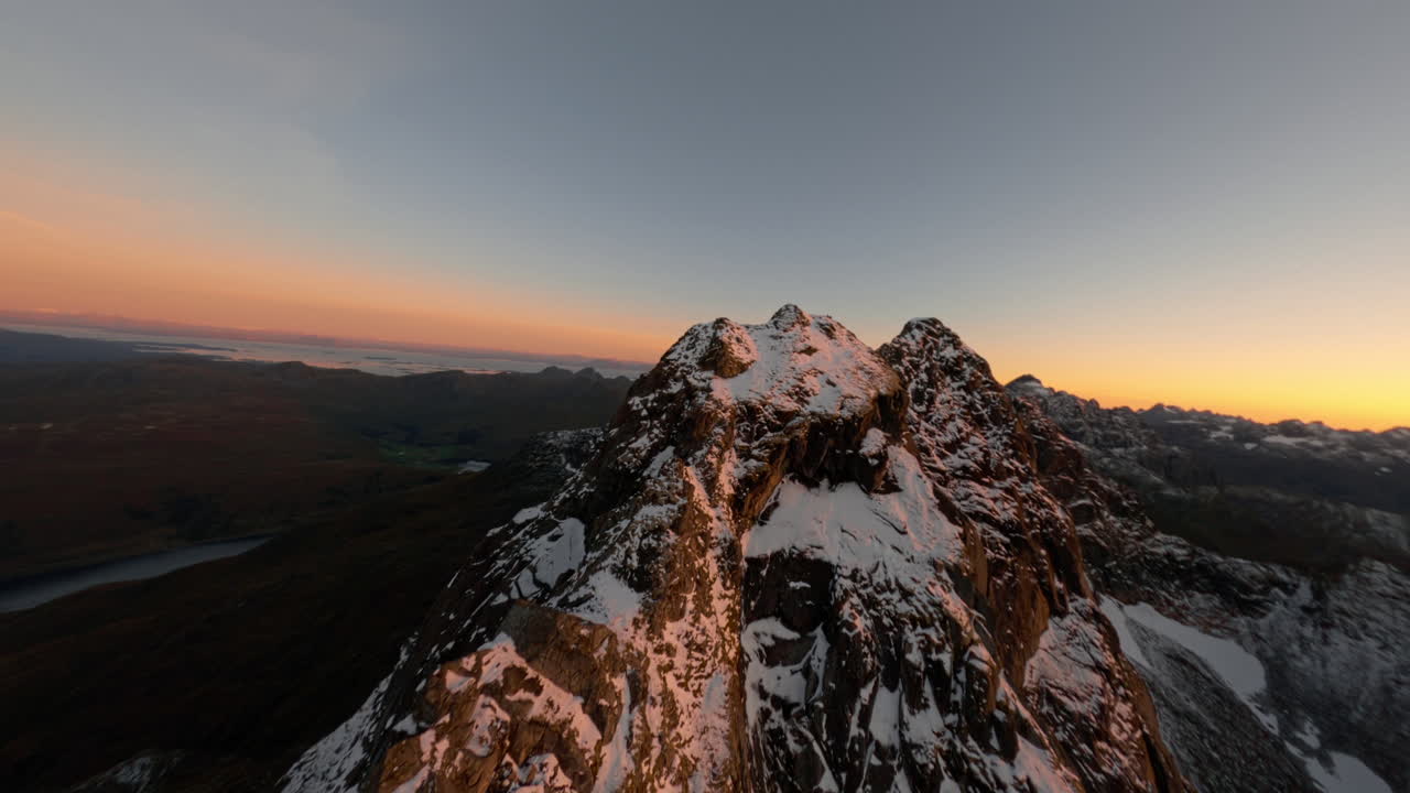 Vista aerea FPV con drone delle cime innevate delle Isole Lofoten in Norvegia al tramonto, impressionante volo a bassa quota