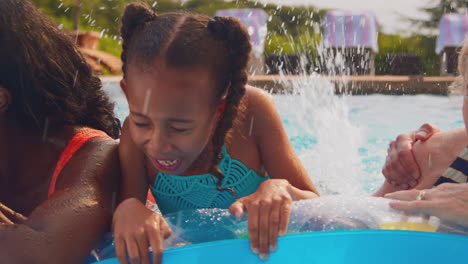 smiling multi-generation family on summer holiday relaxing in swimming pool on airbed