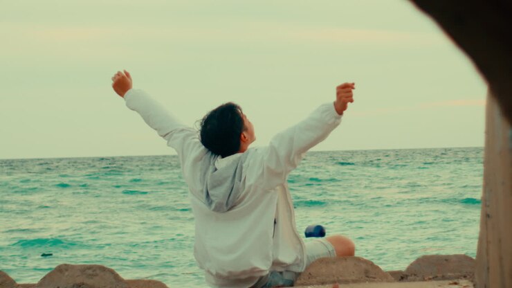 Man Relaxing on the Beach with Arms Raised