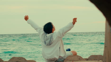 man relaxing on the beach with arms raised