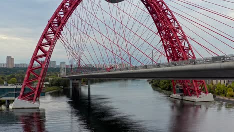 Luftdrohne-Fliegt-In-Der-Nähe-Einer-Riesigen-Roten-Autobahnbrücke-Mit-Starkem-Verkehr,-Moskau,-Russland