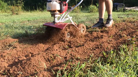 man running tiller in backyard garden