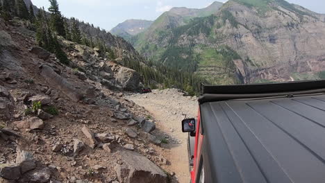 Rooftop-of-4WD-vehicle-creeping-along-on-the-challenging-Poughkeepsie-Gulch-trail-past-boulders-and-sheer-cliff-in-Colorado