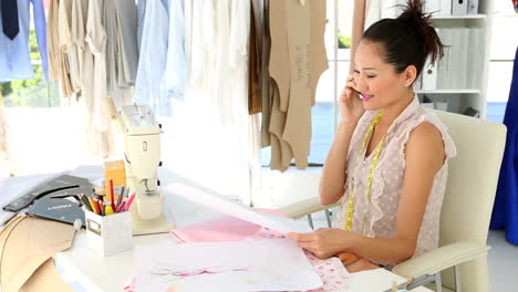 fashion designer sitting at table talking on phone