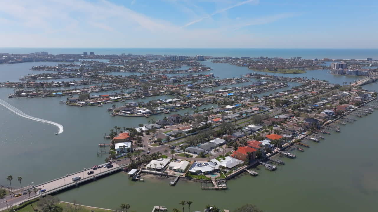 Aerial View of Florida Intracoastal Waterfront Luxury Neighborhood with Vehicle Traffic and Boats on a beautiful sunny blue day