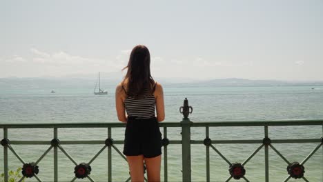 woman walks up to pier to overlook lake constance bodensee in friedrichshafen, germany