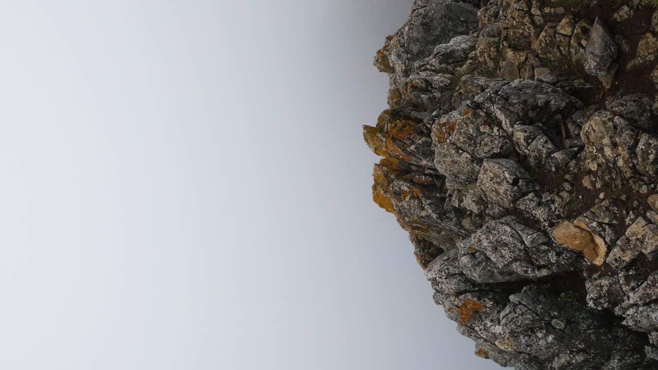 tiro vertical de 4k de un acantilado de montaña delgado y nubes y niebla en la concha, marbella, españa