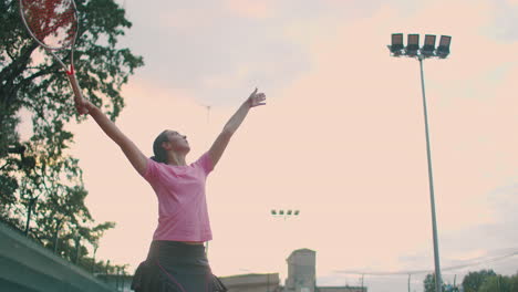 Low-angle-view-in-slow-motion-of-a-young-female-tennis-player-preparing-to-serve-a-tennis-match.-A-woman-athlete-is-powerfully-hitting-a-ball-during-sports-practice.-Commercial-use-footage