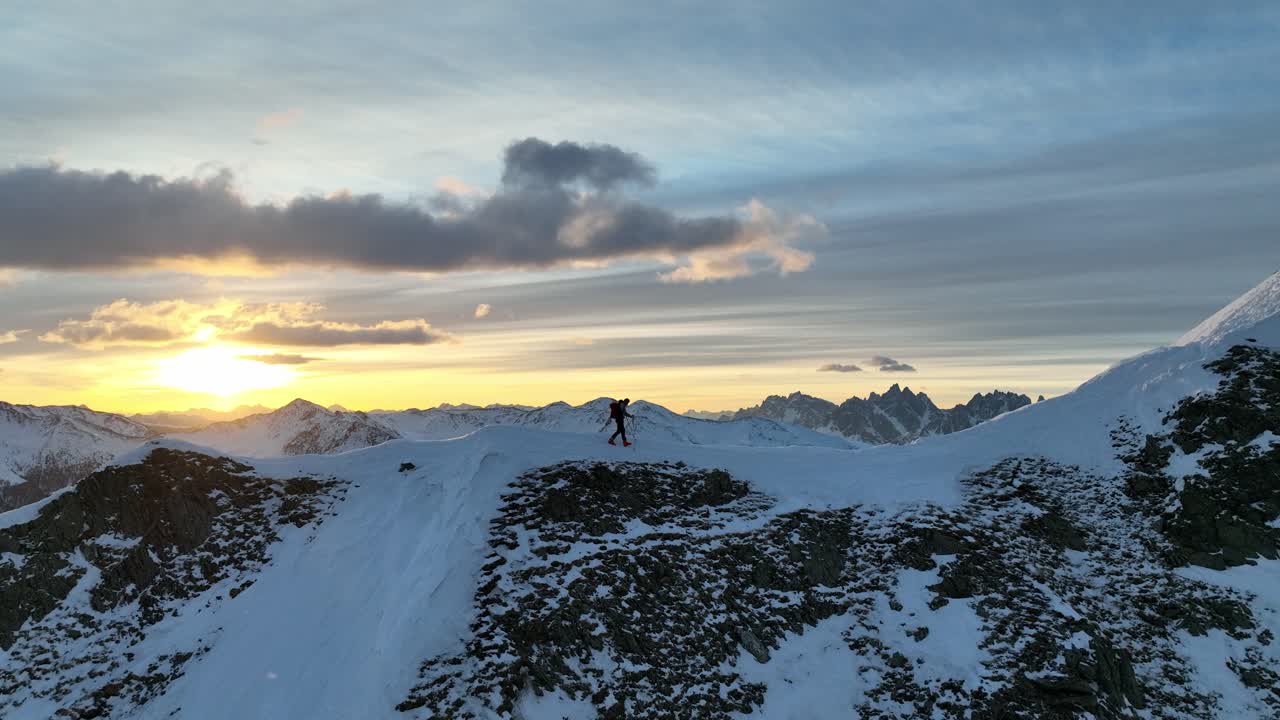 Alpine skier walking on a ridge shortly after sunrise in South Tyrol