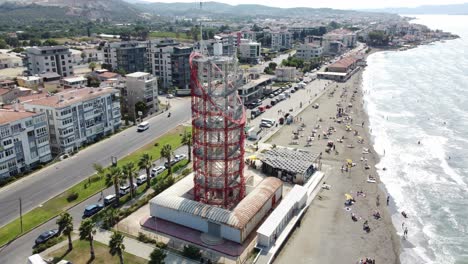 drone-footage-of-Marine-radar-tower-at-the-beach-in-izmir,-blue-eagean-sea-with-a-beach-next-to-it