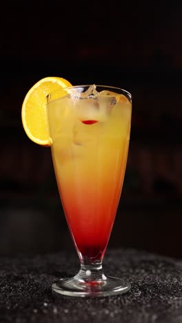 woman garnishing a layered orange and red cocktail