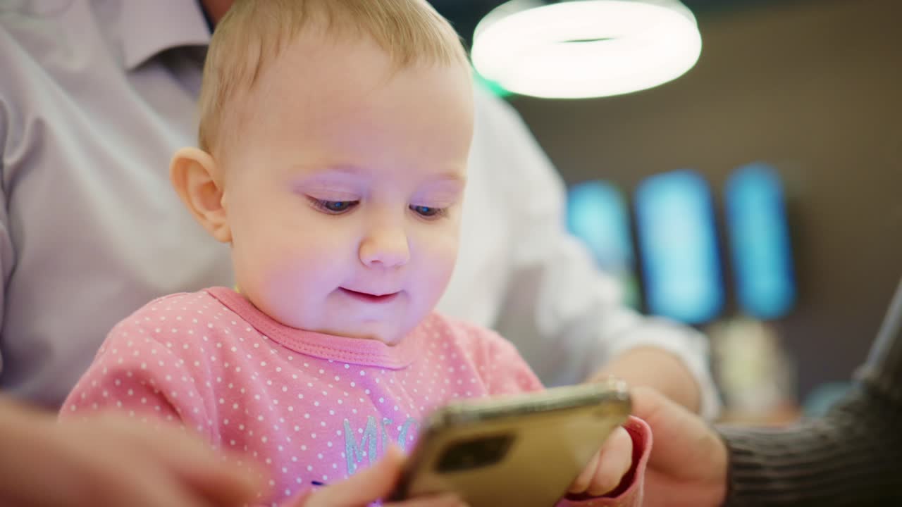 スマートフォンで遊び、笑顔を見せる楽しそうな女の子の赤ちゃん