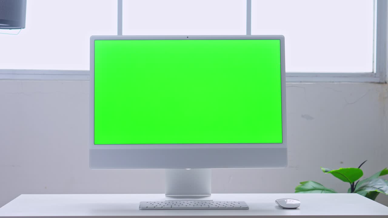 Modern computer with green screen on white desk in office