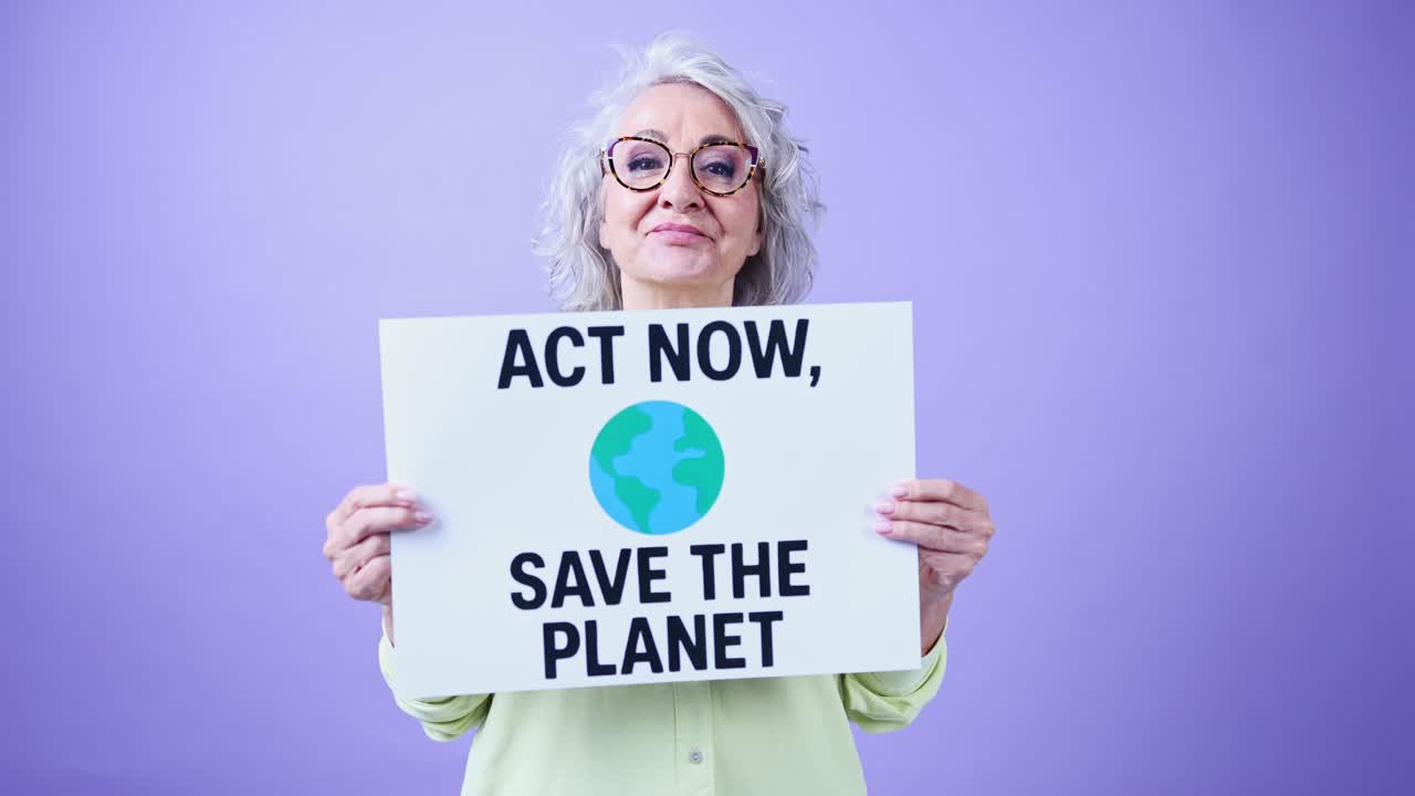 Mujer mayor sosteniendo un cartel de protesta que dice 'Actúa ahora, salva el planeta'