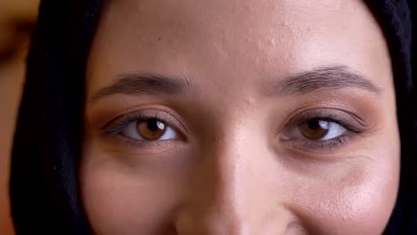 closeup portrait of young beautiful arabian female with pretty brown eyes looking straight at camera with smiling facial expression