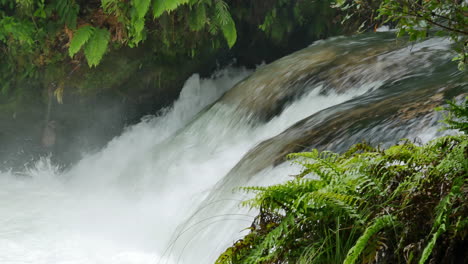close up pan shot of splashing water at tutea waterfall surrounded by green jungle,new zealand