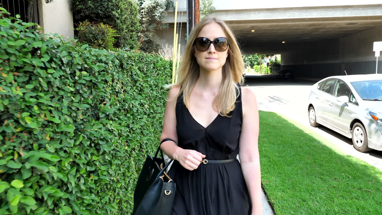 Woman in a Black Dress Walking on the Street