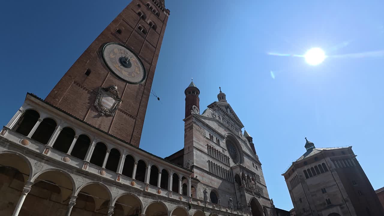 Duomo di Cremona e Torrazzo in Piazza del Comune a Cremona, Lombardia, Italia, che mostrano la facciata romanica e gotica con il campanile in mattoni più alto d'Europa sotto un cielo sereno, scatto dal basso verso l'alto