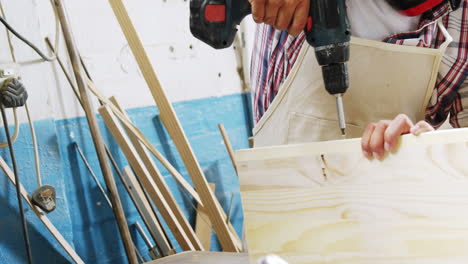 retrato de un carpintero concentrado clavando una tabla de madera