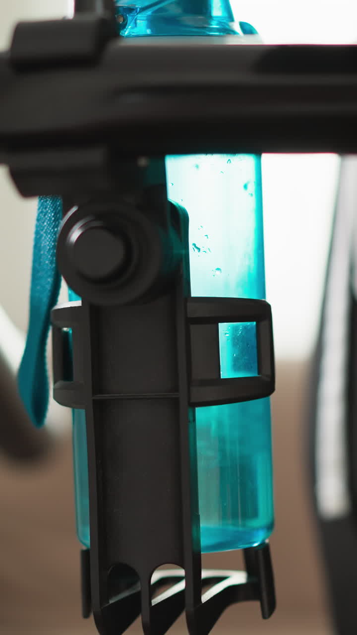 mujer se acerca a la cinta de correr con una botella de agua. deportista pone la botela de agua en el soporte de la máquina de equipo deportivo en casa. condición de vida equilibrada