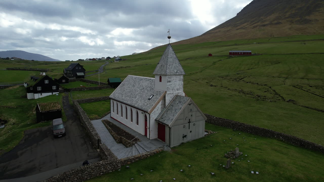 Vi&eth;arei&eth;i church, Faroe Islands: aerial view in orbit of the church and making out the small houses of the town