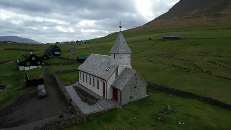 Viðareiði-church,-Faroe-Islands:-aerial-view-in-orbit-of-the-church-and-making-out-the-small-houses-of-the-town