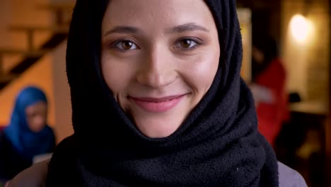 closeup portrait of young beautiful successful muslim businesswoman in black hijab looking at camera and smiling cheerfully