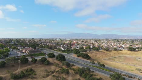 drone establishing of suburban landscape merging into green parkland with mountains in far background
