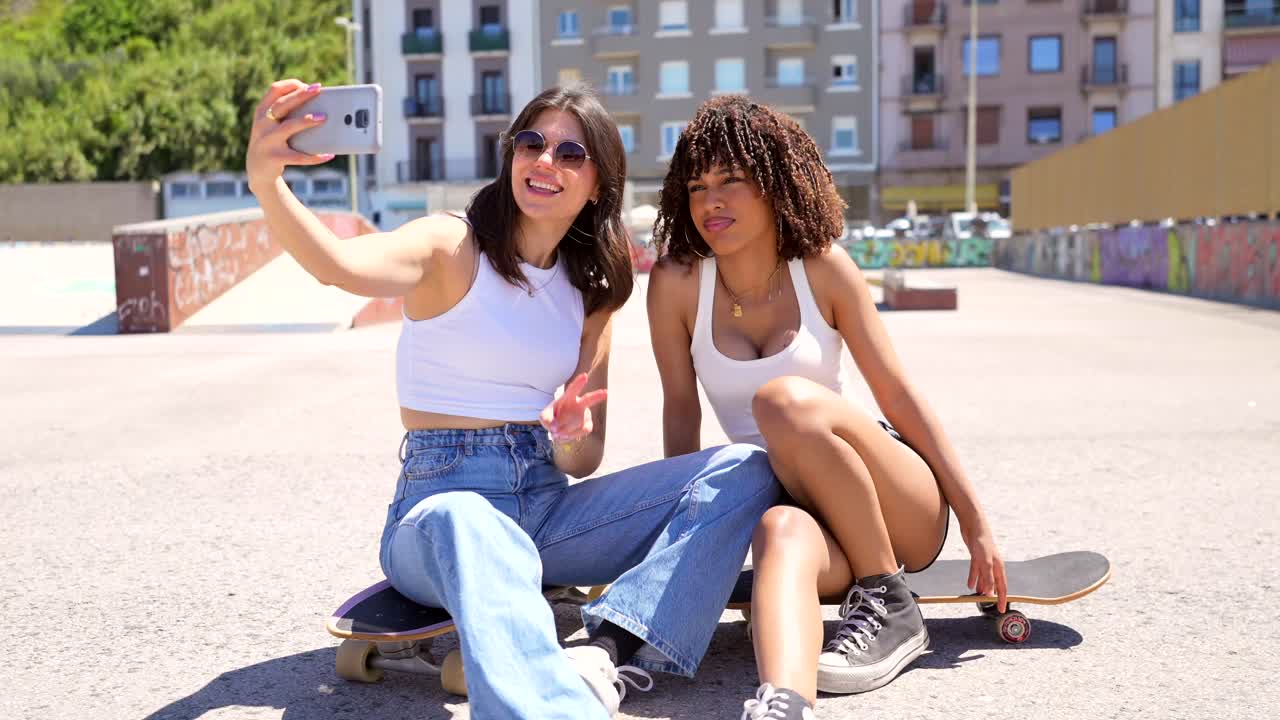 Due giovani donne che si fanno un selfie sullo skateboard in un ambiente urbano