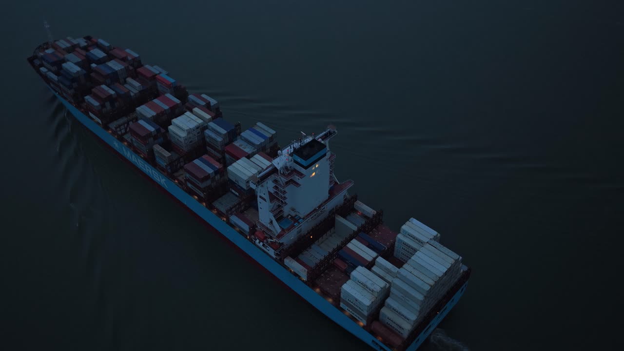 Freight container ship gliding over Elbe River at sunset twilight