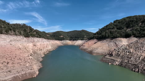 aerial view lush green sunlit ter river woodland valley, sau reservoir during low water shortage, catalan