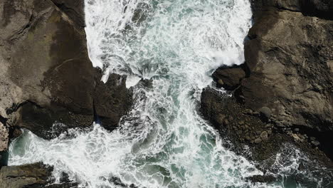 water continuously eroding the ancient volcanic rock as it splashes into a small cove