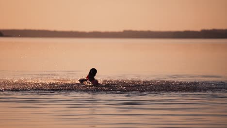silhouette of boy at sunset in the river. silhouette of a child playing splash water in river