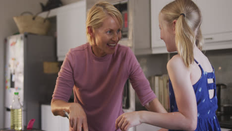 vista lateral de una mujer caucásica con su hija en la cocina