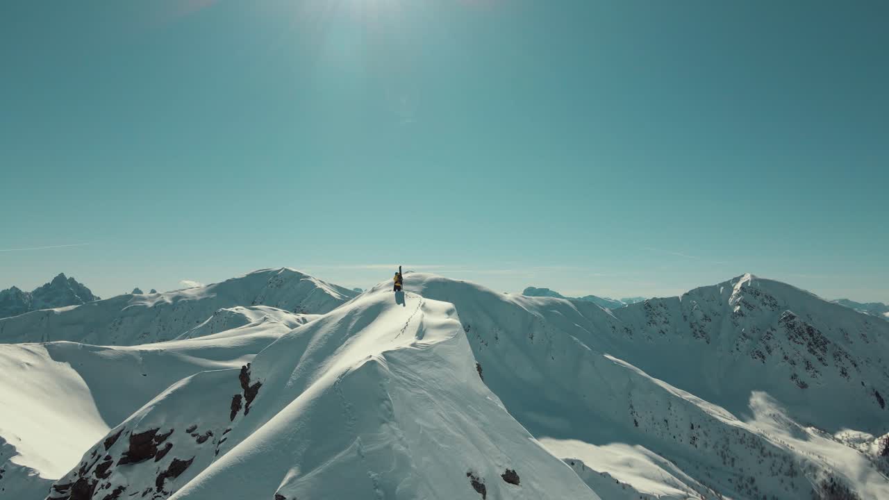 배낭에 스키를 싣고 정상에 서 있는 프리라이더