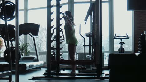 woman performing barbell squats in a gym