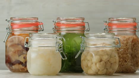 fermented champignons, jar with marinated mushrooms on wooden table, traditional salted marinated asian food.