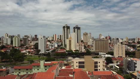 aerial rising through houses, tall residential buildings in background, bauru, brazil