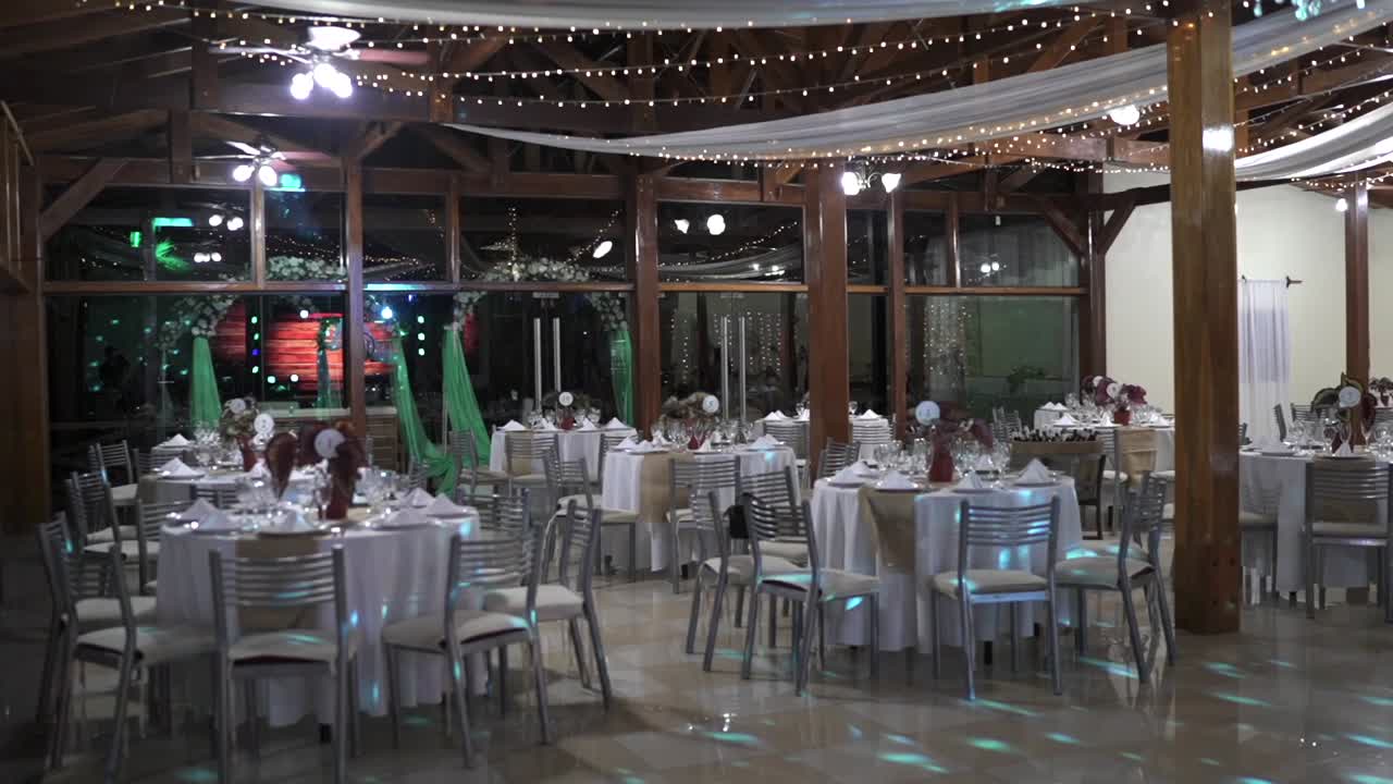 Elegantly decorated wedding event hall with tables and lights in night environment