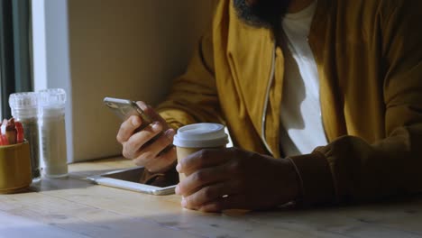 Mid-section-of-mixed-race-man-using-mobile-phone-in-cafeteria-4k