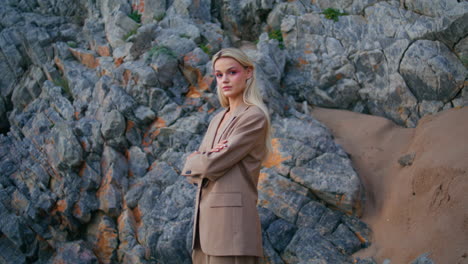 beach girl modeling rocks at sandy shore. attractive blonde in fashionable suit