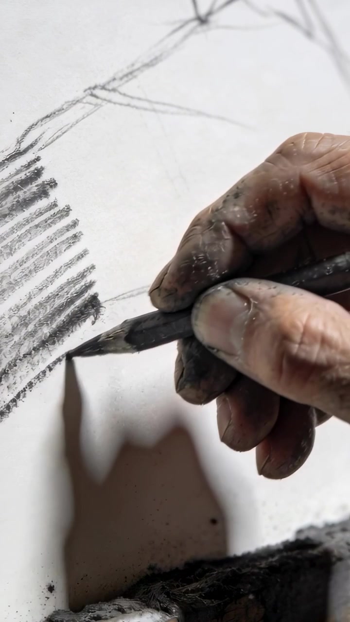 Vertical video: Defining diagonal from left hatch, hand deepening left tone with charcoal on paper