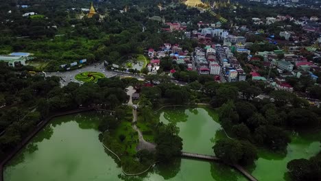 a breathtaking rising aerial over kandawgyi lake, yangon, myanmar, revealing the iconic shwedagon pagoda and the u htaung bo roundabout. perfect for showcasing the city's landmarks and natural beauty