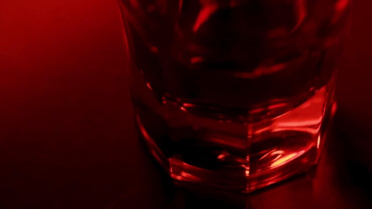 Alcohol glass with red and blue police lights, macro shot close up view. Alcohol crime and danger concept video.