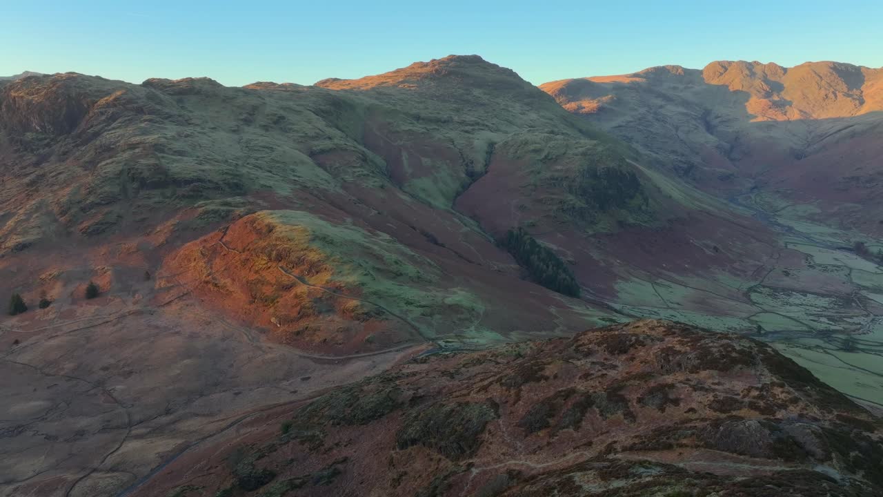 Mountain peaks and crags catching winter dawn light. Slow rotating panning shot. Langdales, English Lake District, Cumbria, UK.