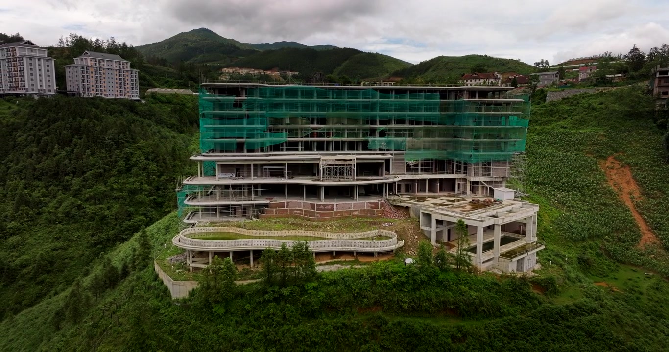 Khách sạn bỏ hoang ở Sa Pa, Việt Nam, nhìn từ trên cao bằng drone giữa núi non và thảm thực vật dày đặc, cảnh quay kéo lùi chậm