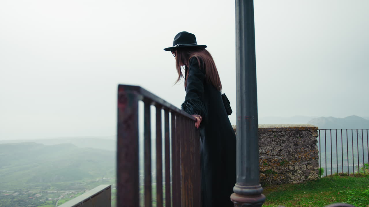 Woman Watching Over The Railing Admiring The Natural Landscape Below The Town