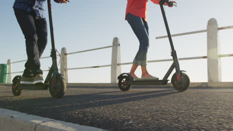 senior couple using electronic scooters alongside beach