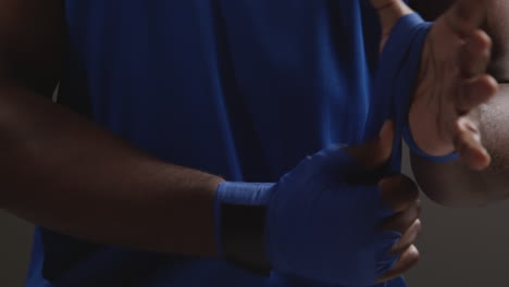 close up of male boxer wrapping hands with protective bandages before boxing match or training session